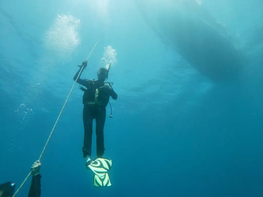 Underwater image of a scuba diver ascending with vibrant fins in the deep blue ocean.